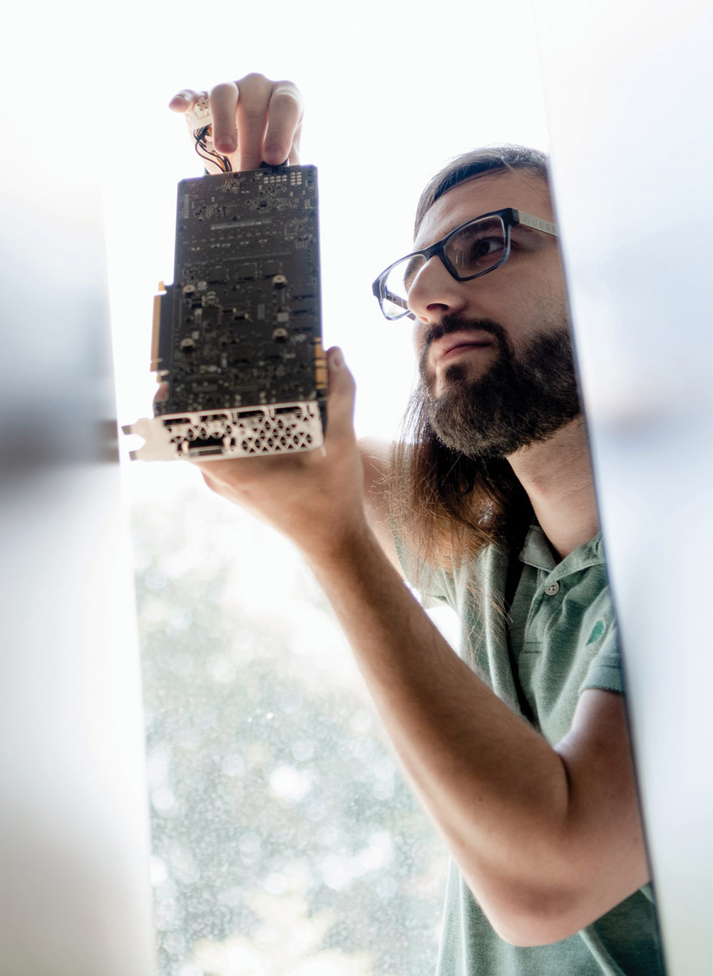 Student holding up computer circuit board looking intently